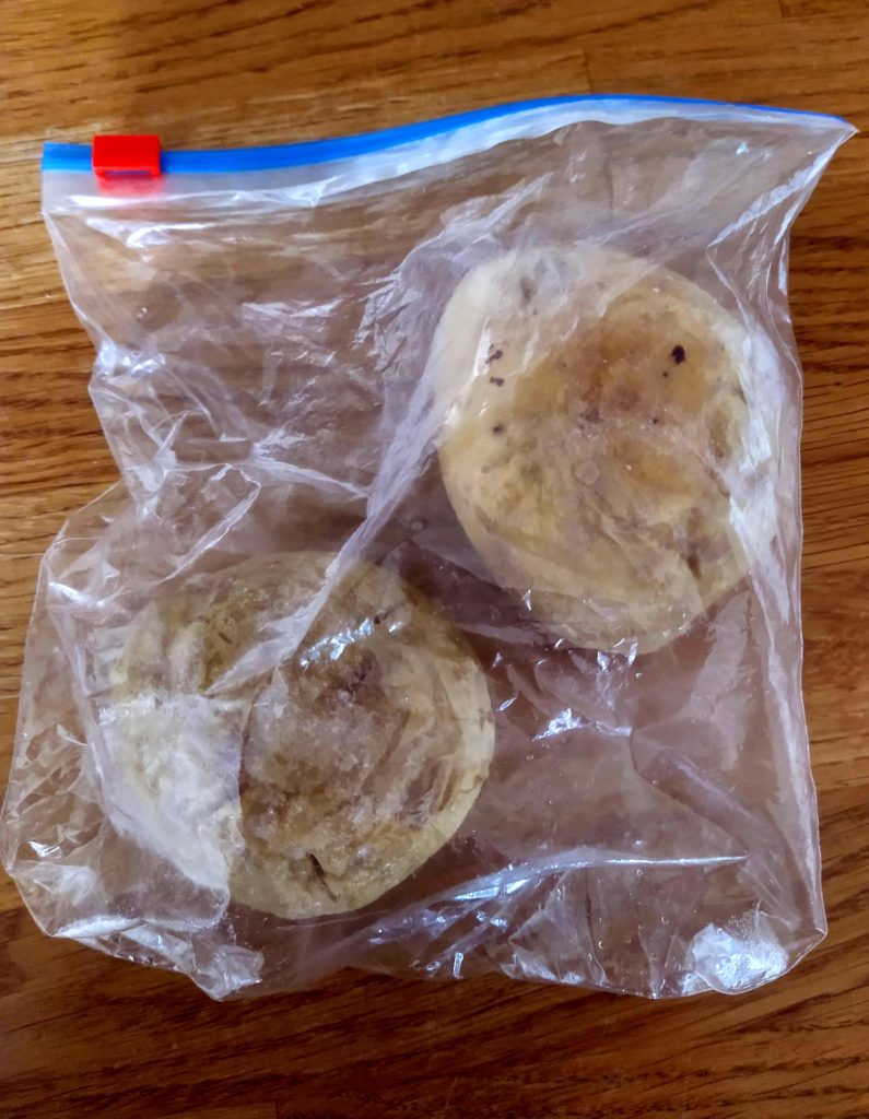 A plastic freezer bag with two frozen jacket potatoes in. 