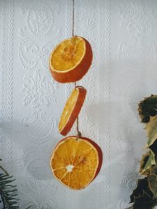 Three orange slices hang using twine
