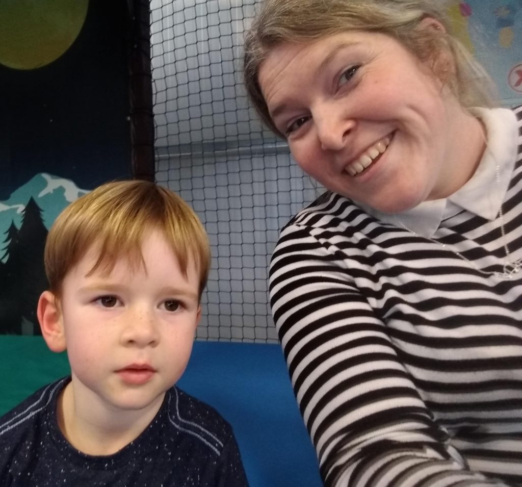 A young boy and his mum sat together. Mum is wearing a black and white striped jumper with a faux collar that she bought from the charity shop