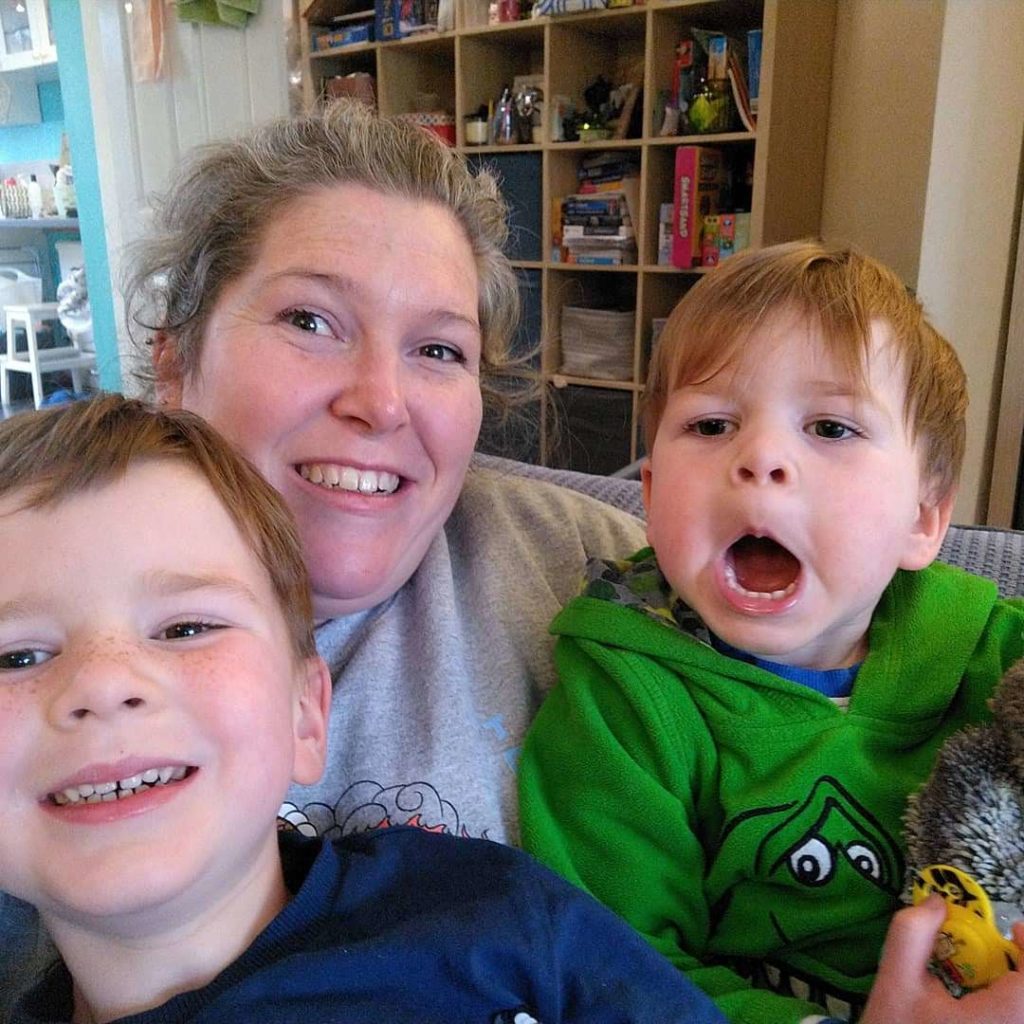 A mum with her two cheeky boys sit together and pose with silly faces