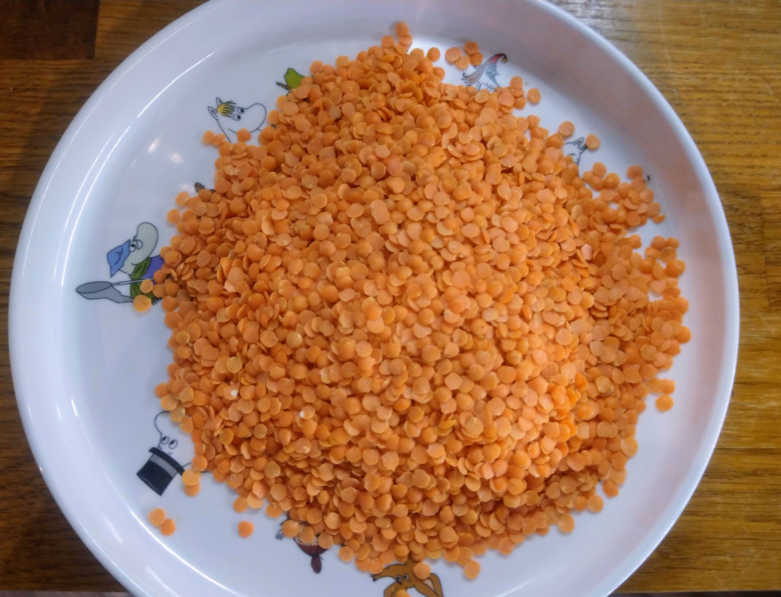 A children's white Moomin plate with a pile of red lentils